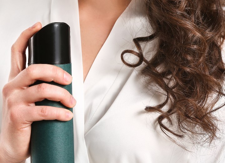 Mujer que está usando laca para el cabello